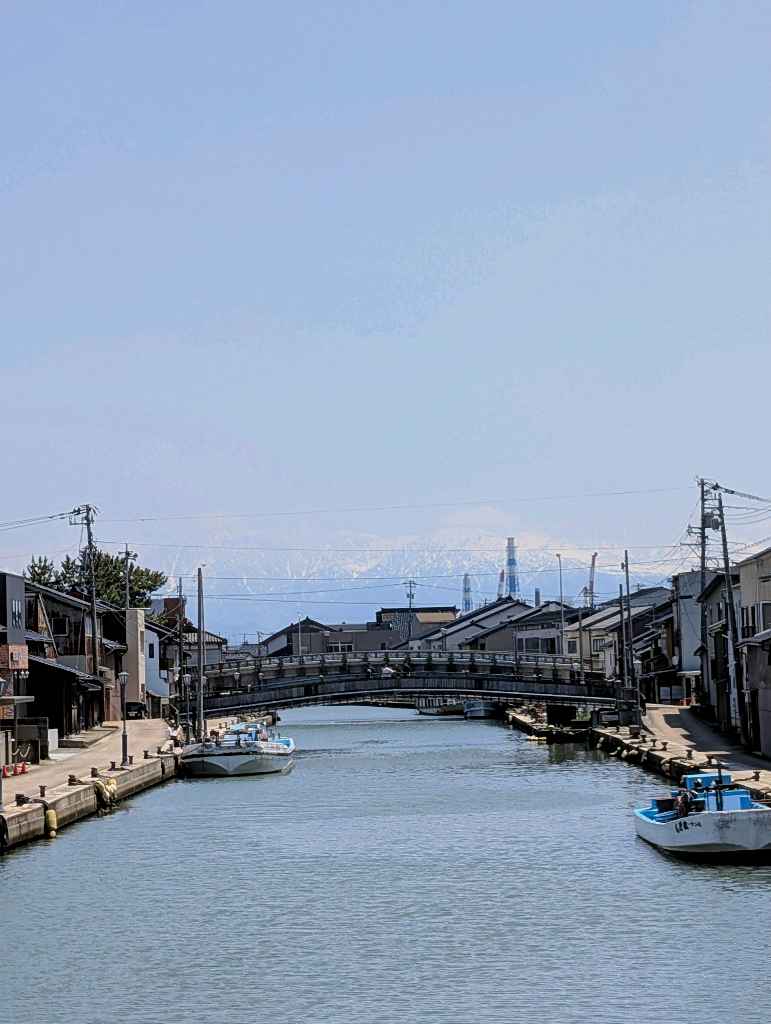 新湊内川エリア - 内川の両岸には漁船が係留され、街並みと奥に見える立山連峰は素敵な眺め
中の橋からの眺めが個人的には好き！

川沿いにはカフェやホテルもあるので、次は泊まって夜の眺めを楽しむのも悪く… - photo 12
